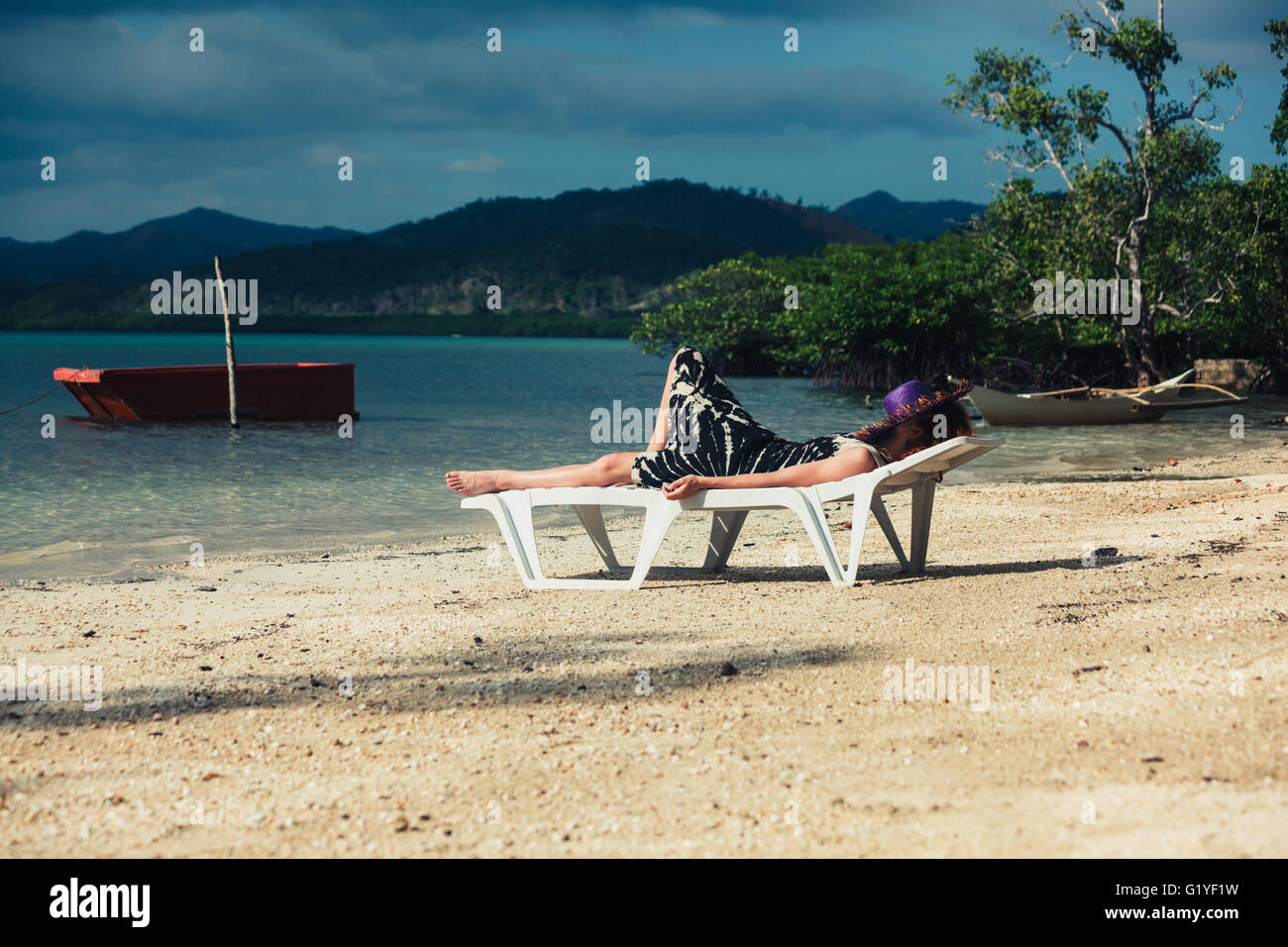 A young woman is relaxing on a sunbed on a tropical beach Stock Photo ...