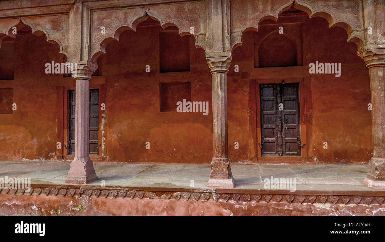 Ancient architecture of India with red clay walls, scalloped arches, and large wooden doors. Stock Photo