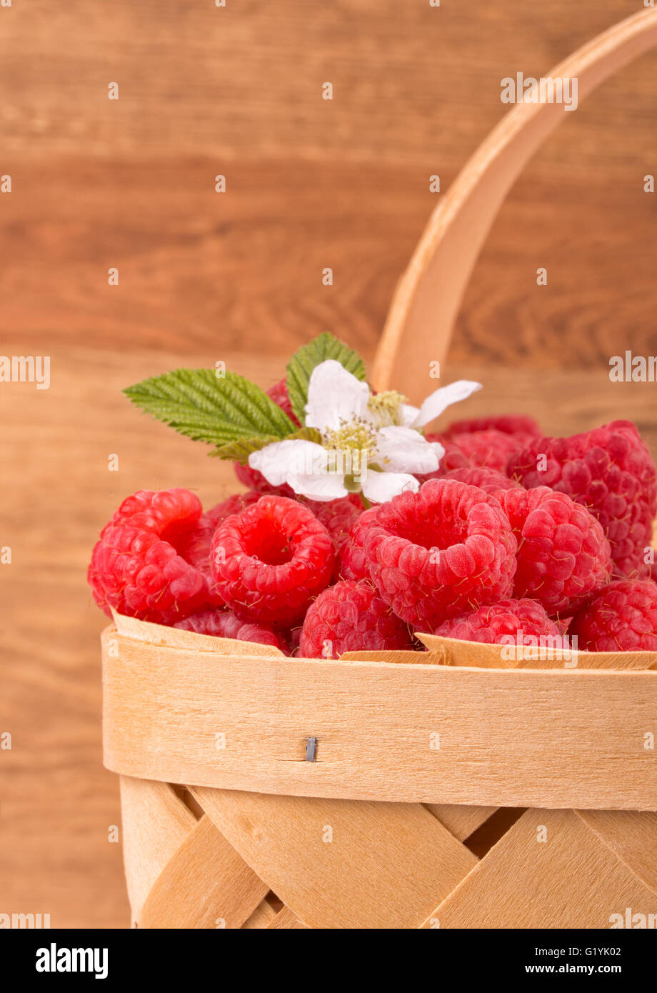 Basket with fresh raspberries, against wooden background Stock Photo