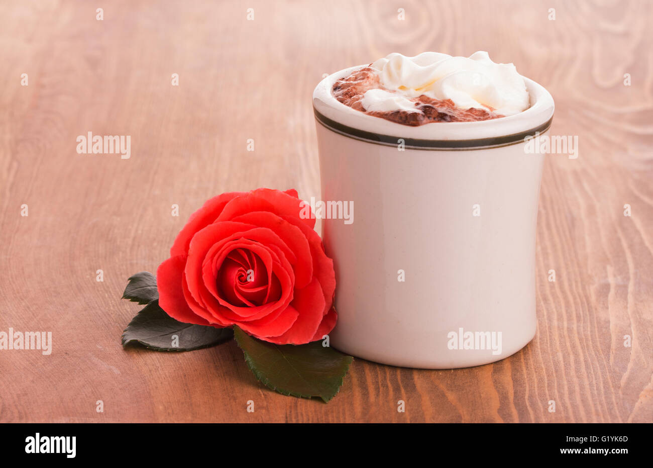 Romantic red rose with a cup of hot chocolate on wooden table - concept of a sweet gesture Stock Photo