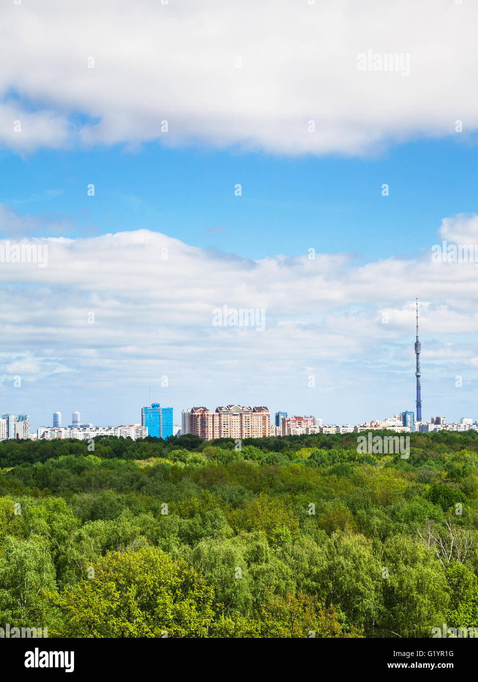 green forest and city on horizon under cloudy blue sky in summer day ...