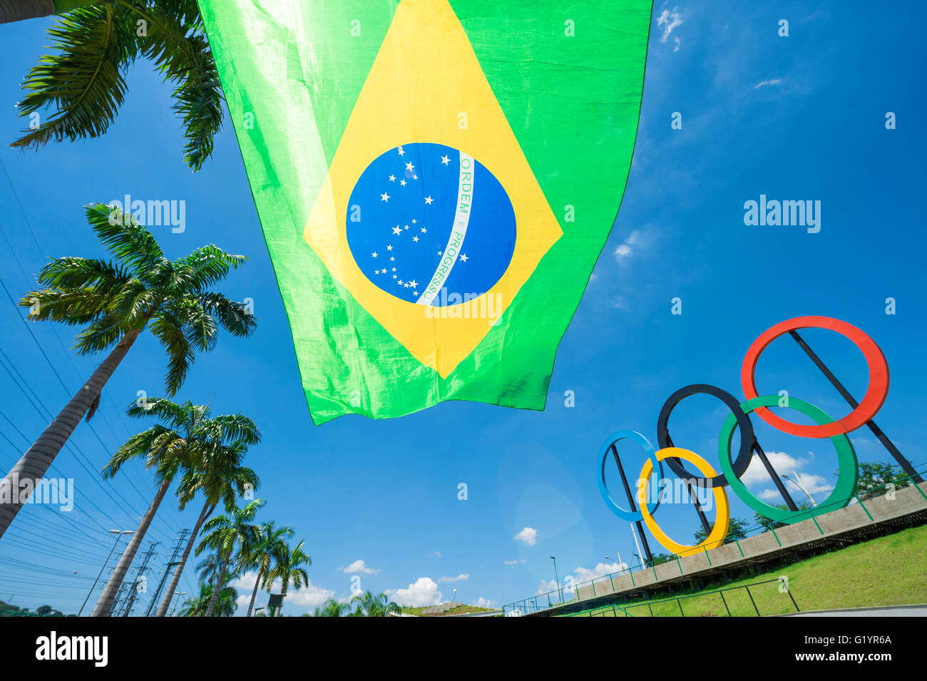 RIO DE JANEIRO - MARCH 18, 2016: A Brazil flag hangs in front of a display of Olympic rings in Parque Madureira Park, Zona Norte Stock Photo