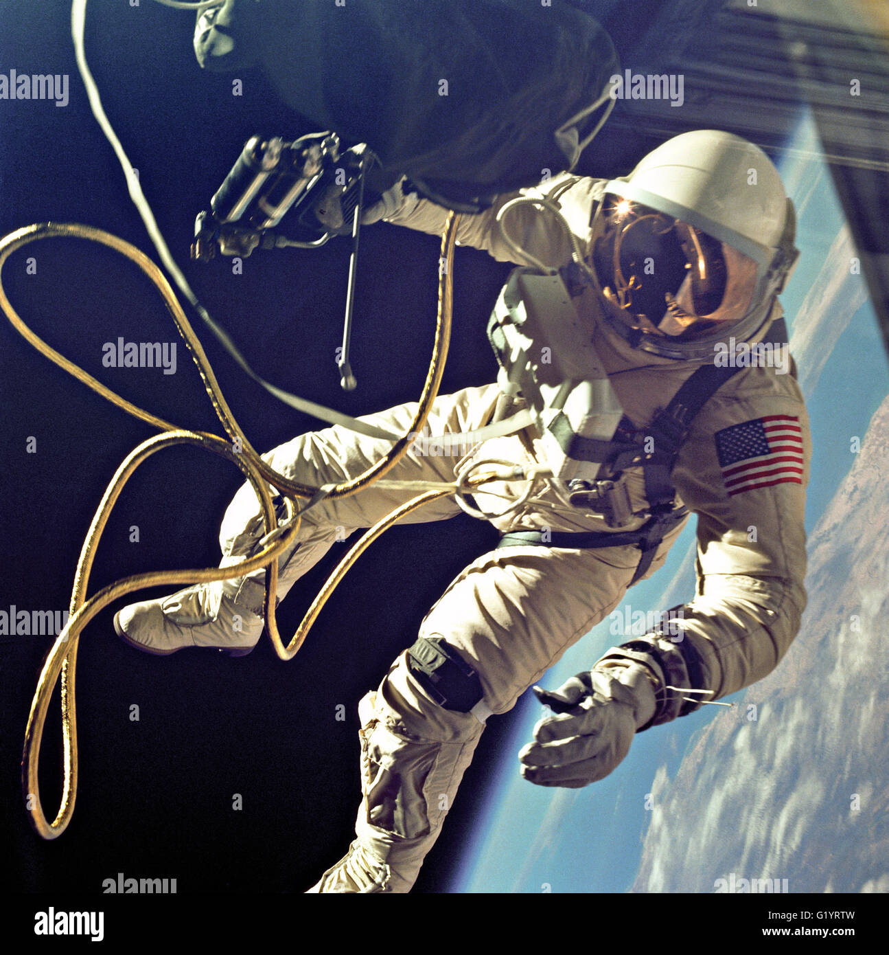 NASA astronaut Ed White floats in the microgravity of space outside the Gemini 4 spacecraft with the blue of the Earth below during the first spacewalk by an American June 3, 1965 in Earth Orbit. White was attached to the spacecraft by a 25 foot umbilical line and a 23-ft. tether line, both wrapped in gold tape to form one cord. In his right hand White carries a Hand Held Self Maneuvering Unit which is used to move about the weightless environment of space. Stock Photo