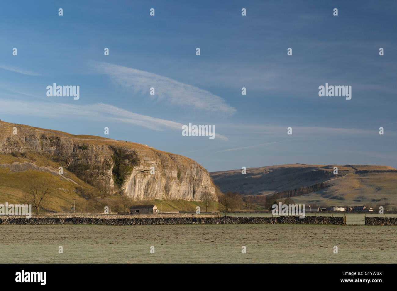 Scenic Wharfe Valley (rolling hills & moors, sunlit high limestone cliff (Kilnsey Crag) & deep blue sky - Wharfedale, Yorkshire Dales, England, UK. Stock Photo