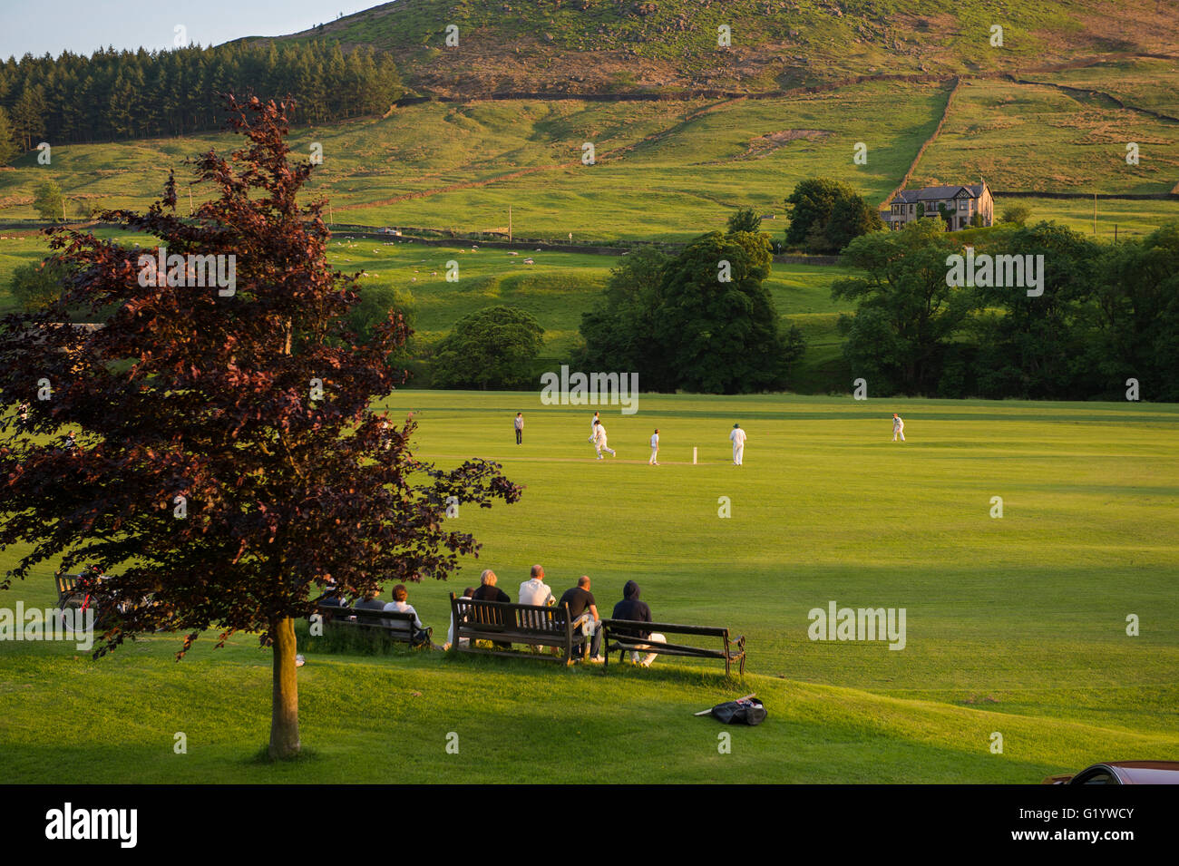 An idyllic, rural setting for spectators to sit and watch a sunny, summer's evening cricket match - Burnsall,  Yorkshire Dales, England, Stock Photo