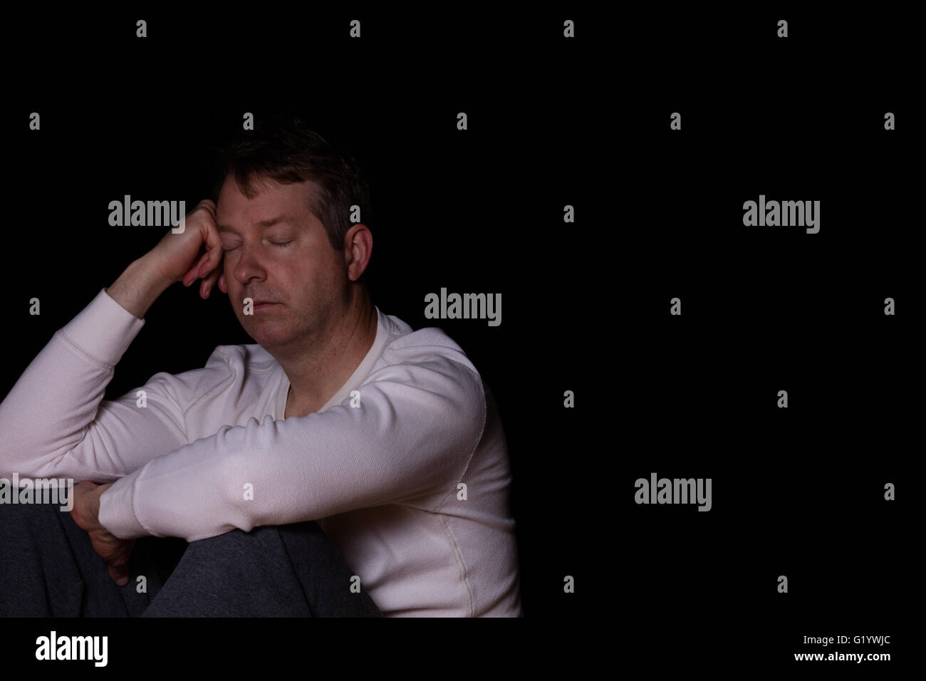 Side view of depressed mature man with eyes closed in thought.  Dark background with copy space available. Stock Photo