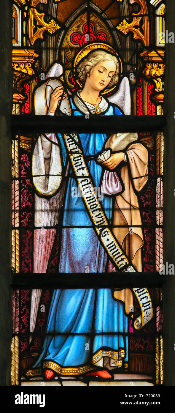 LIER, BELGIUM - MAY 16, 2015: Stained Glass window in St Gummarus Church in Lier, Belgium, depicting and Angel holding a money p Stock Photo