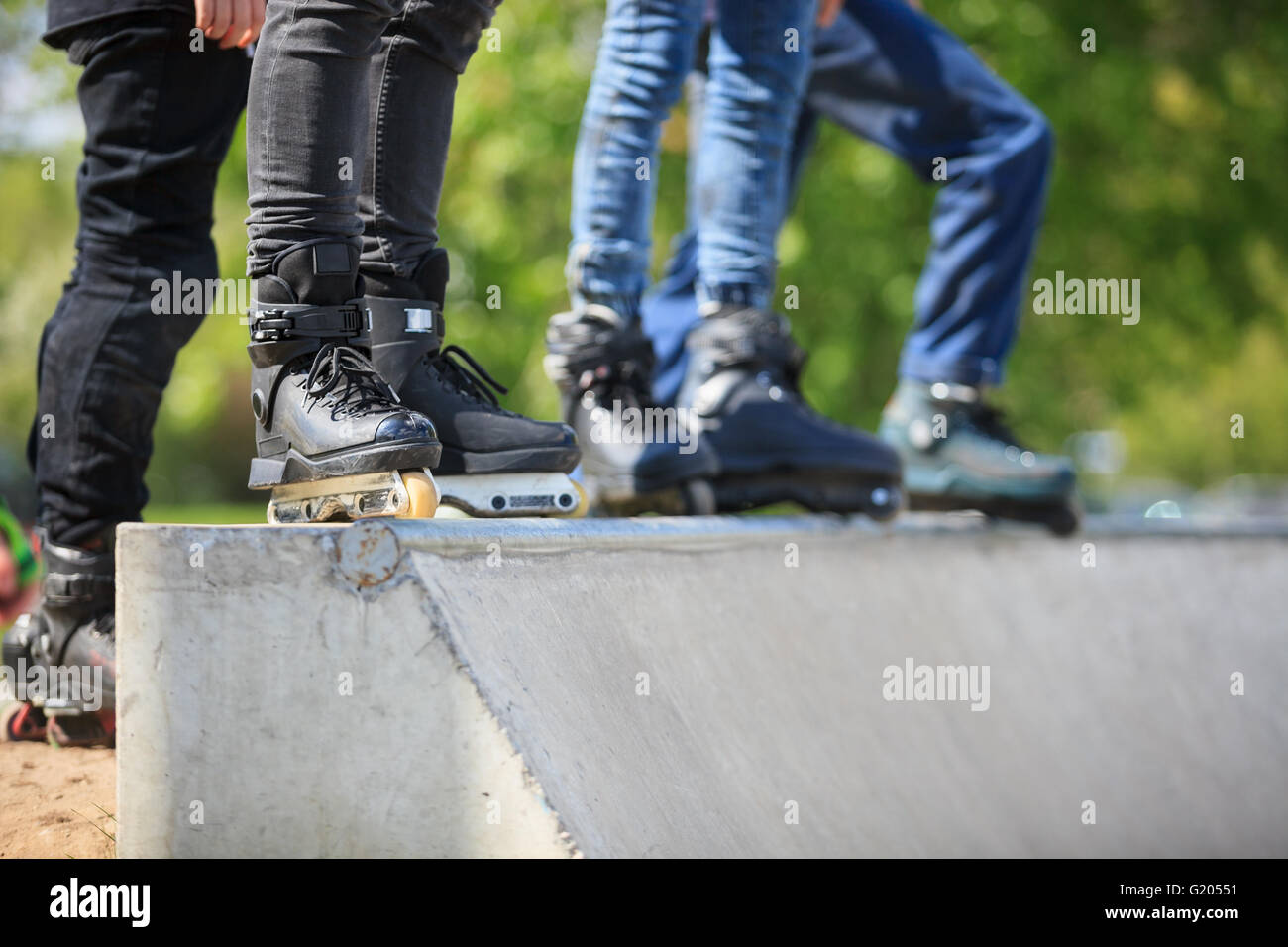 Feet of rollerblader wearing aggressive inline skates standing on top of concrete ramp in