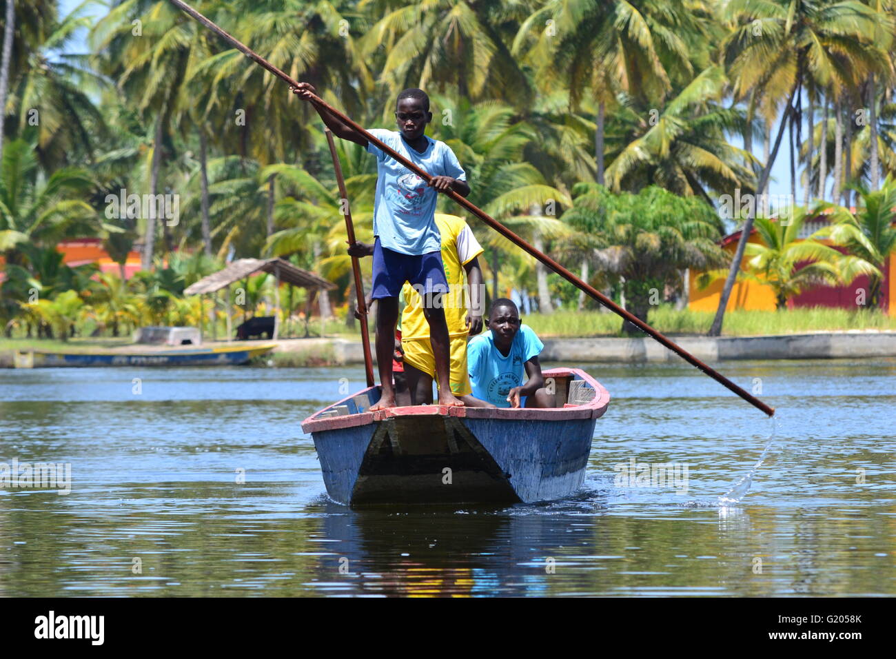 Young African boys rowing a traditional canoe in Ivory Coast Stock