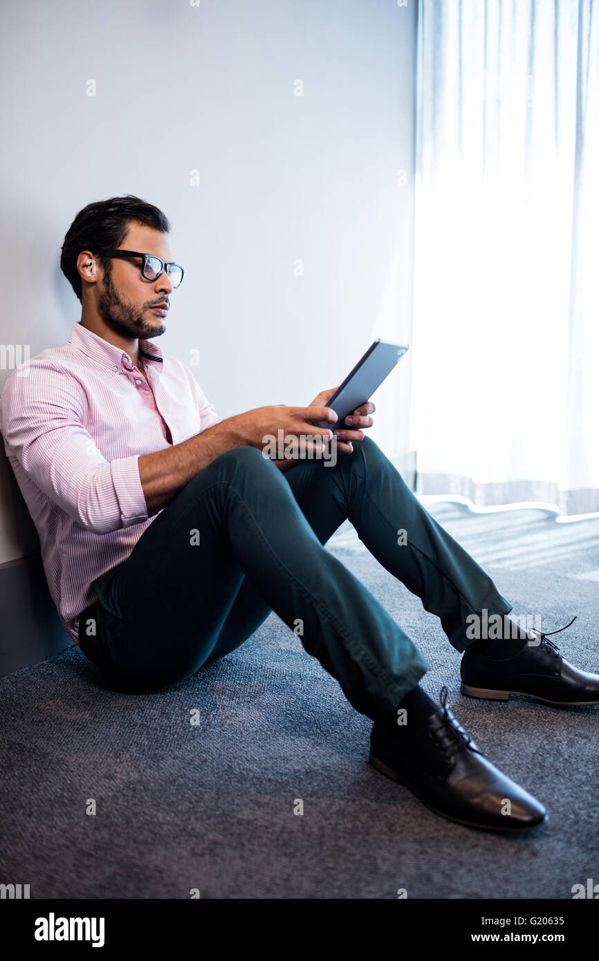 Serious businessman using tablet computer while sitting on the floor Stock Photo