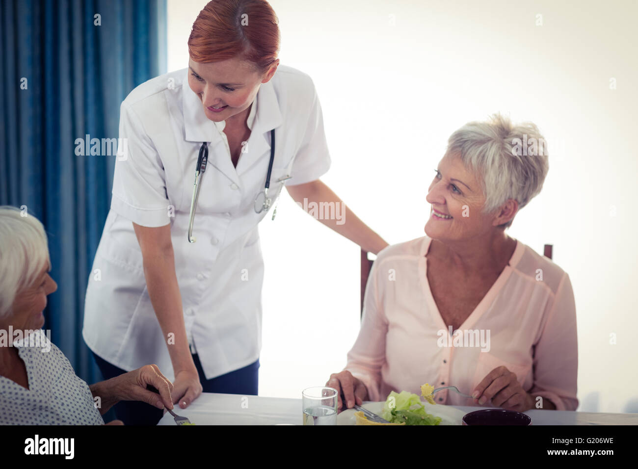 Pensioners at lunch with nurse Stock Photo