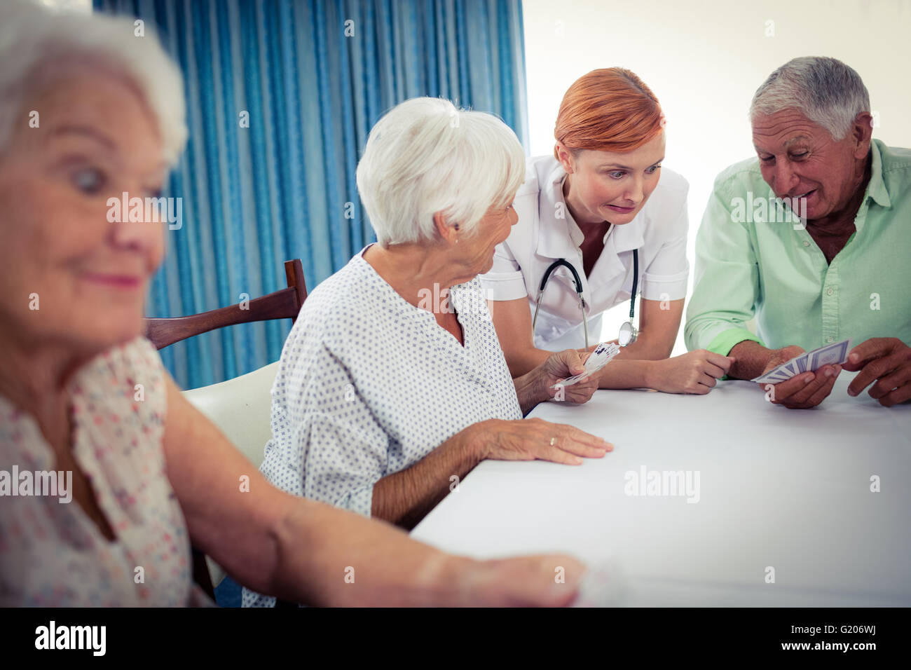 Pensioners playing cards with nurse Stock Photo