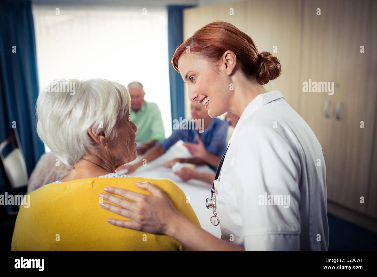 Pensioners playing cards with nurse Stock Photo