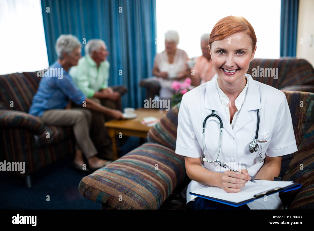 Portrait of a nurse with pensioners in background Stock Photo
