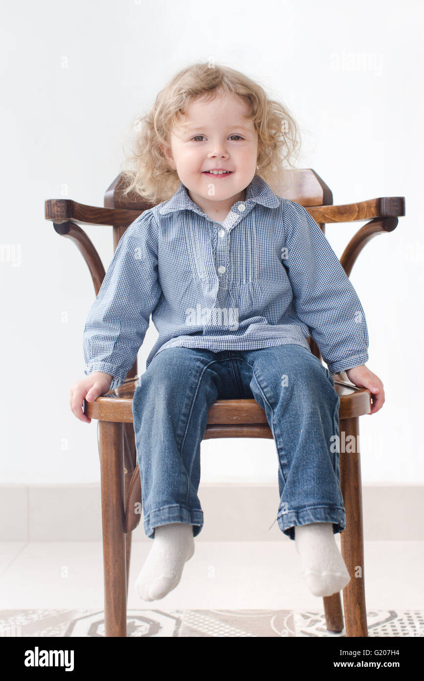 Two year old child sitting on chair full body Stock Photo
