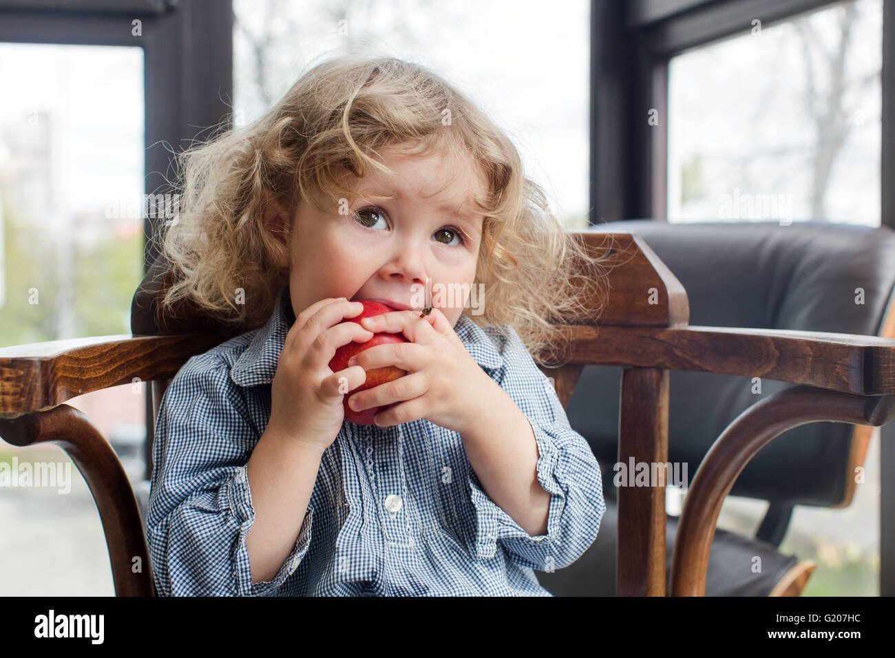 little child eating red apple indoors Stock Photo