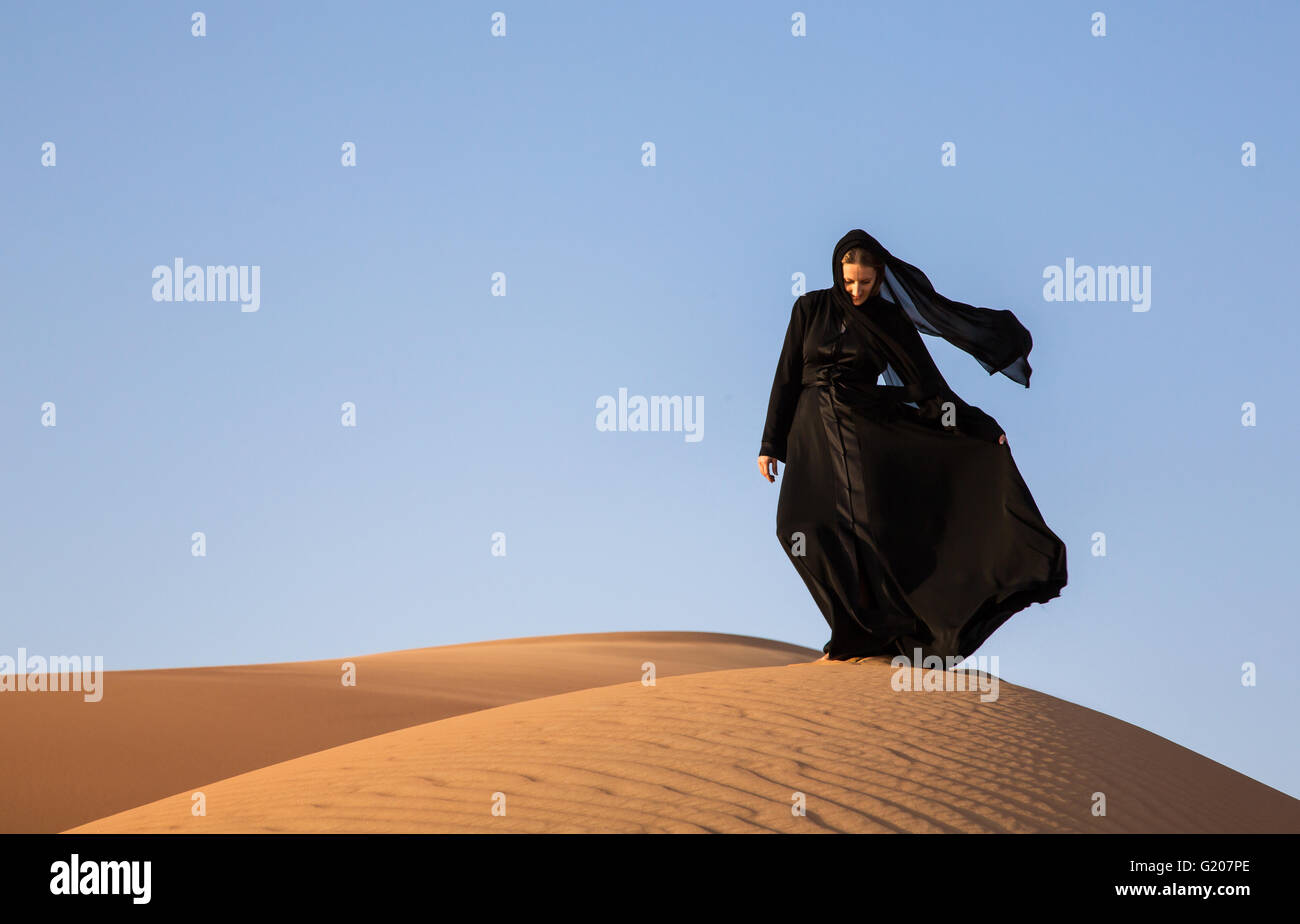 A woman in abaya in sand dunes in Liwa Desert, Aby Dhabi, UAE Stock Photo