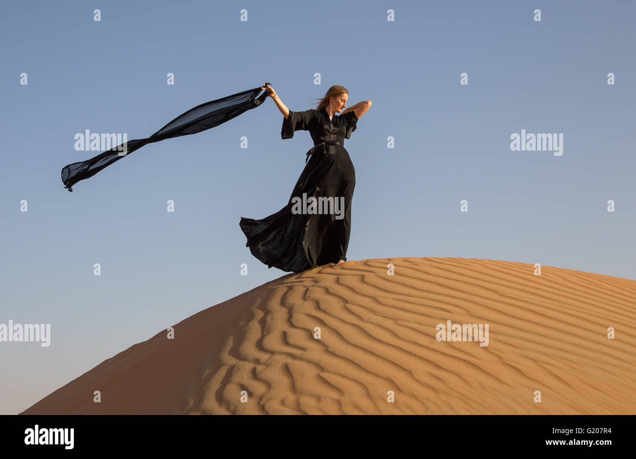A woman in an abaya in sand dunes in Liwa Desert, Abu Dhabi, UAE Stock Photo