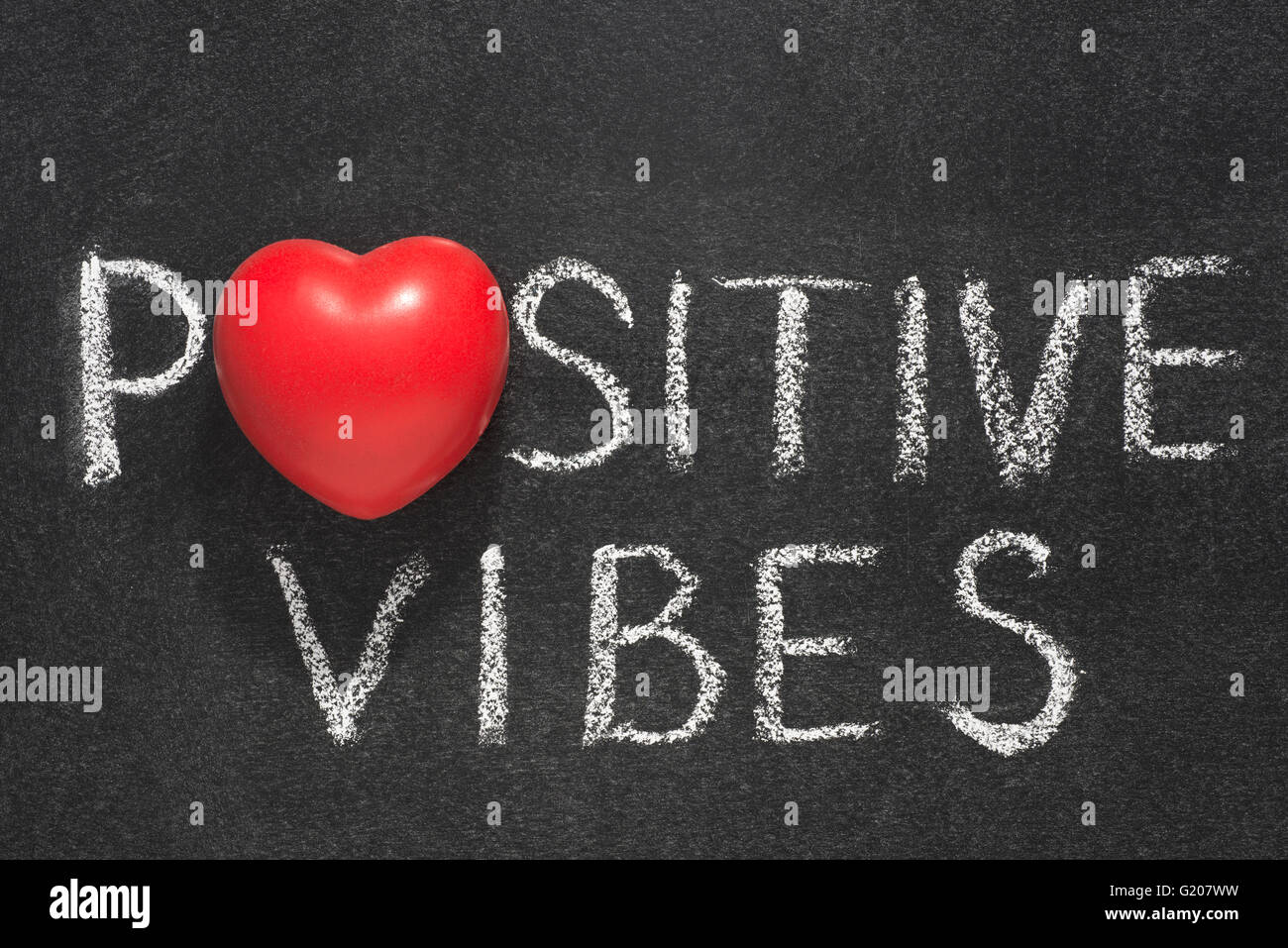 positive vibes phrase handwritten on blackboard with heart symbol instead of O Stock Photo