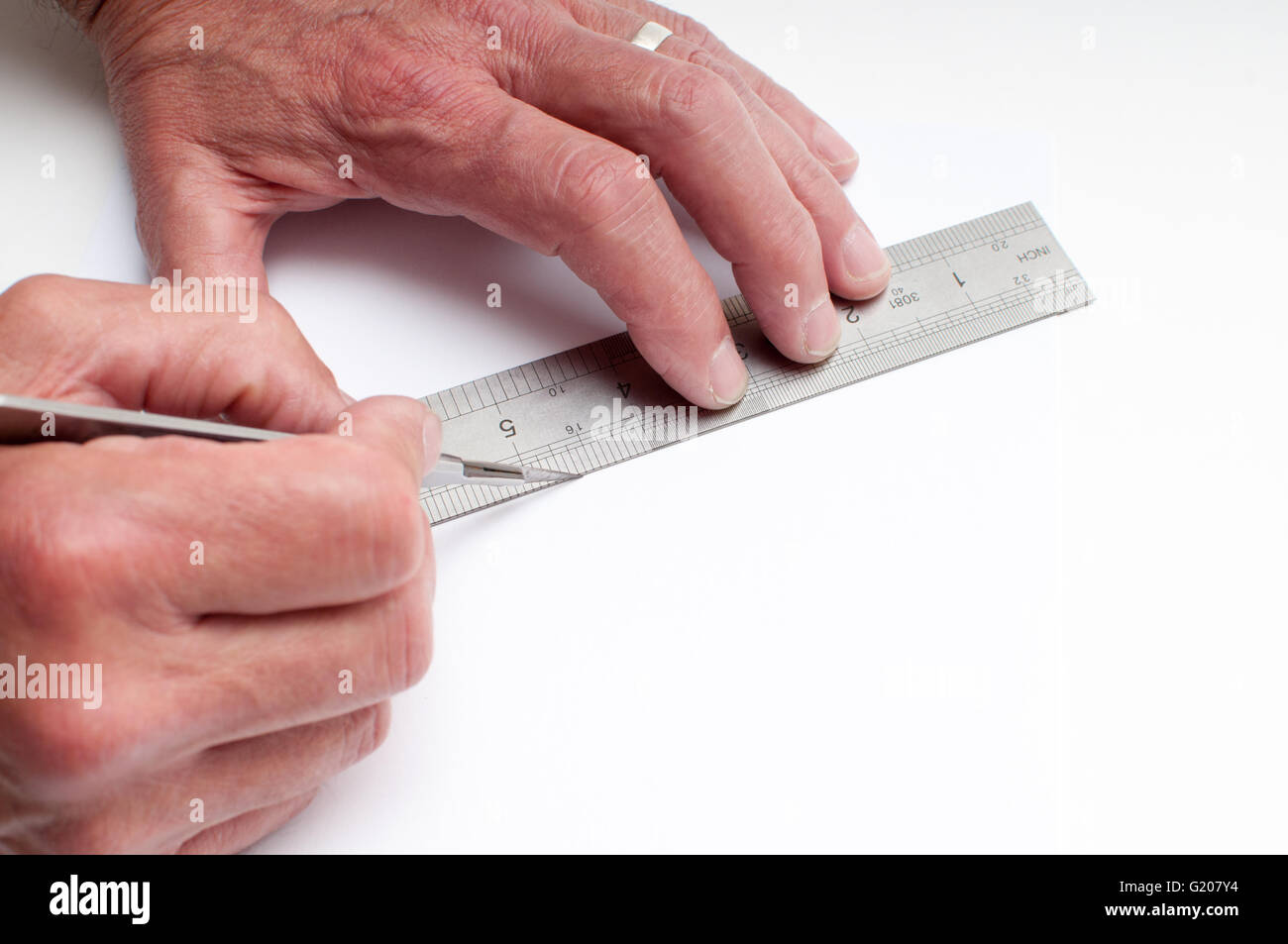 An artist cutting white paper with a craft knife and measuring with a