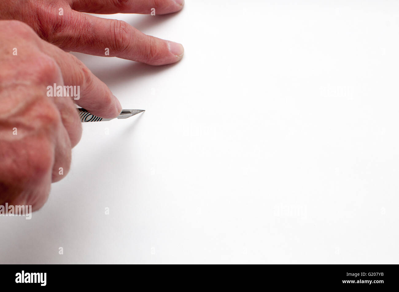 An artist cutting white paper with a craft knife and measuring with a