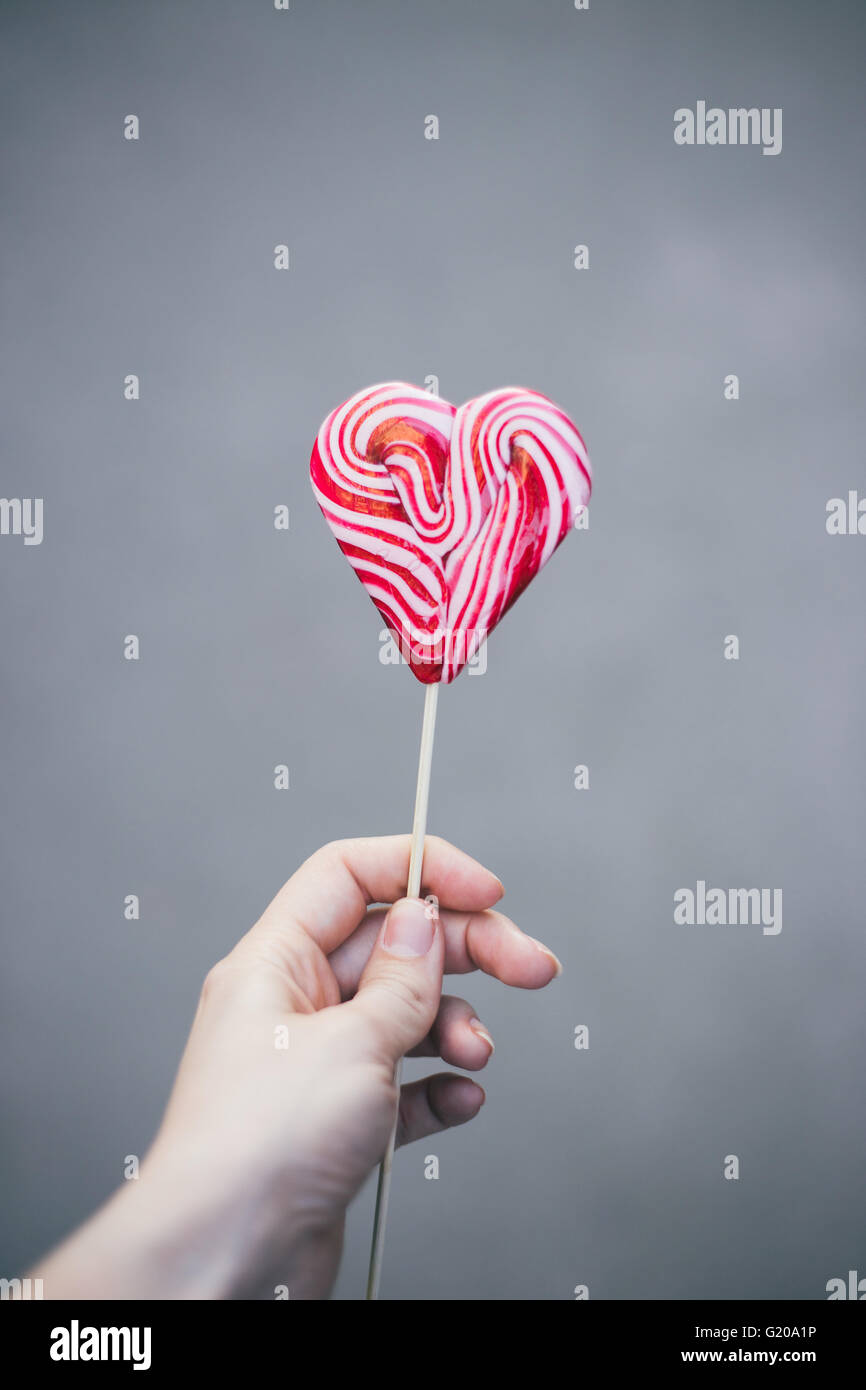 Woman's hand holding heart shaped lollipop Stock Photo - Alamy