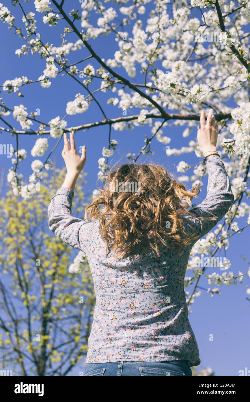 Young woman jumping in front of a spring blossom tree Stock Photo