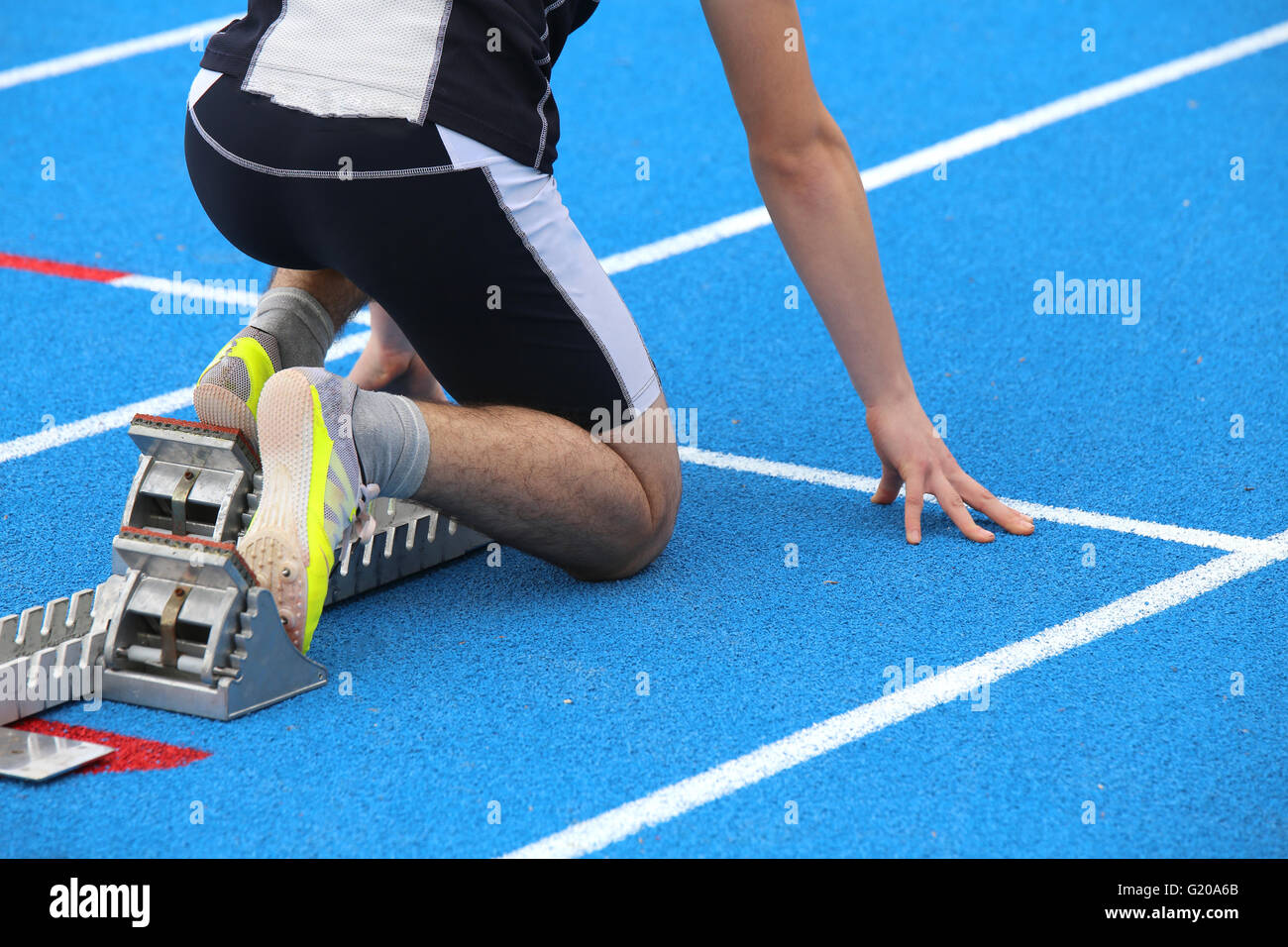 muscular young athlete in the starting blocks of a athletic track