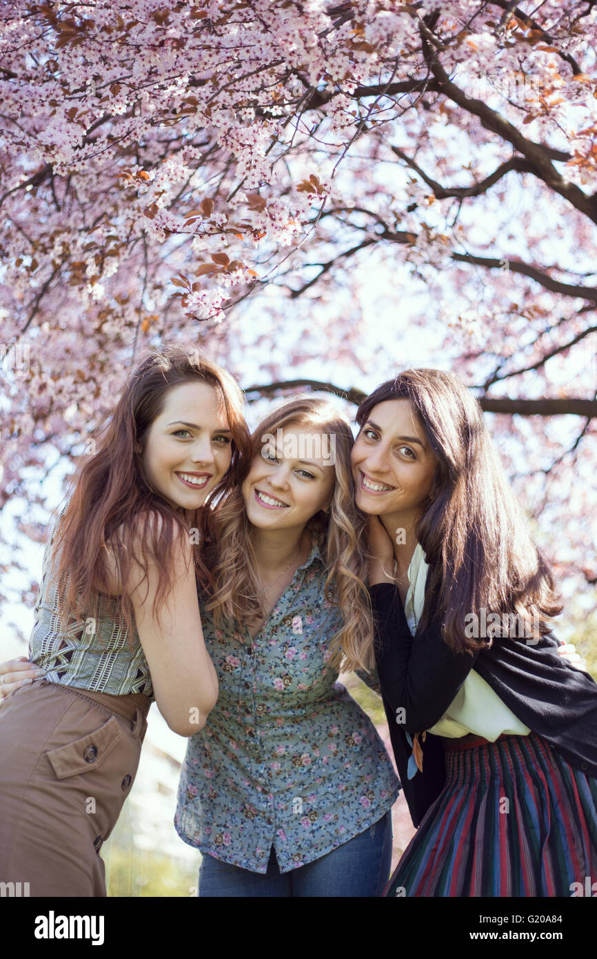 Three girls smiling in front of a spring blossom tree Stock Photo - Alamy