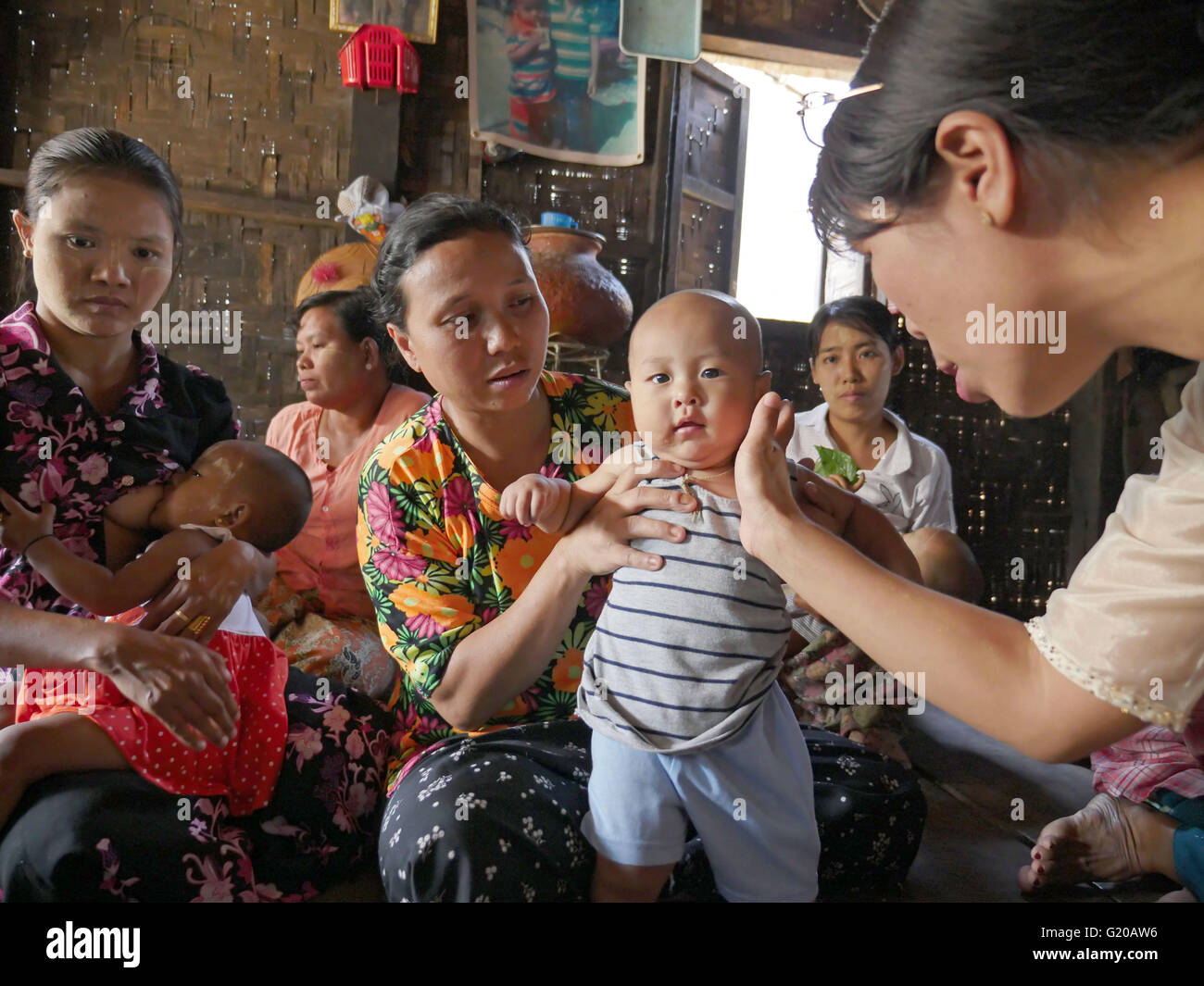 MYANMAR Hlaing Thayer, a slum of Yangon where people were relocated after the 2008 typhoon. MCHAN is active in this area with its community based health program. Visiting a house where MCHAN performs health check-ups and conducts workshops. MCHAN nurse Monica Yaw Myu Hli examines a healthy baby. Stock Photo