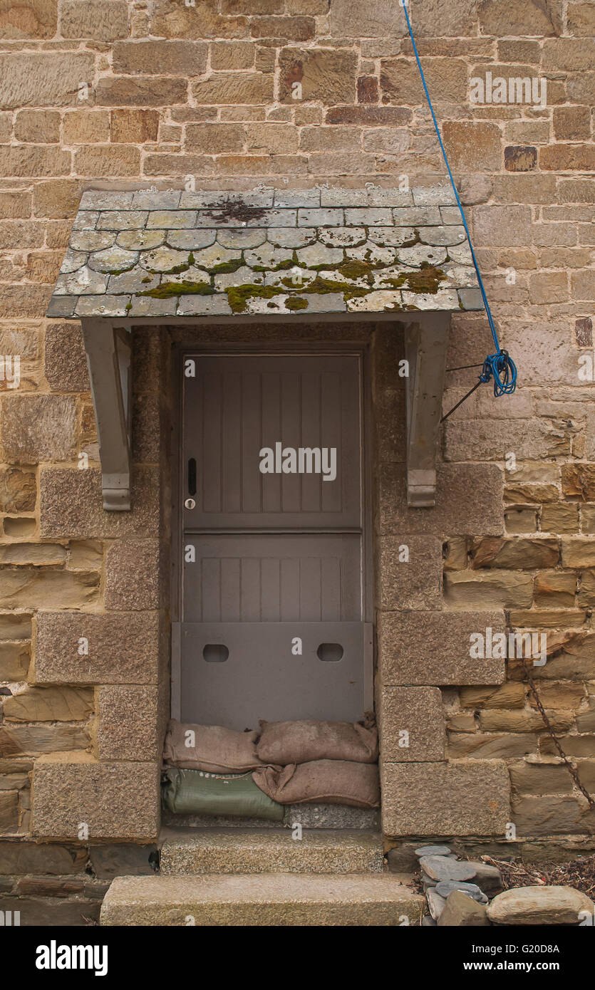 A doorway to a cottage with flood defence sand bags. Stock Photo