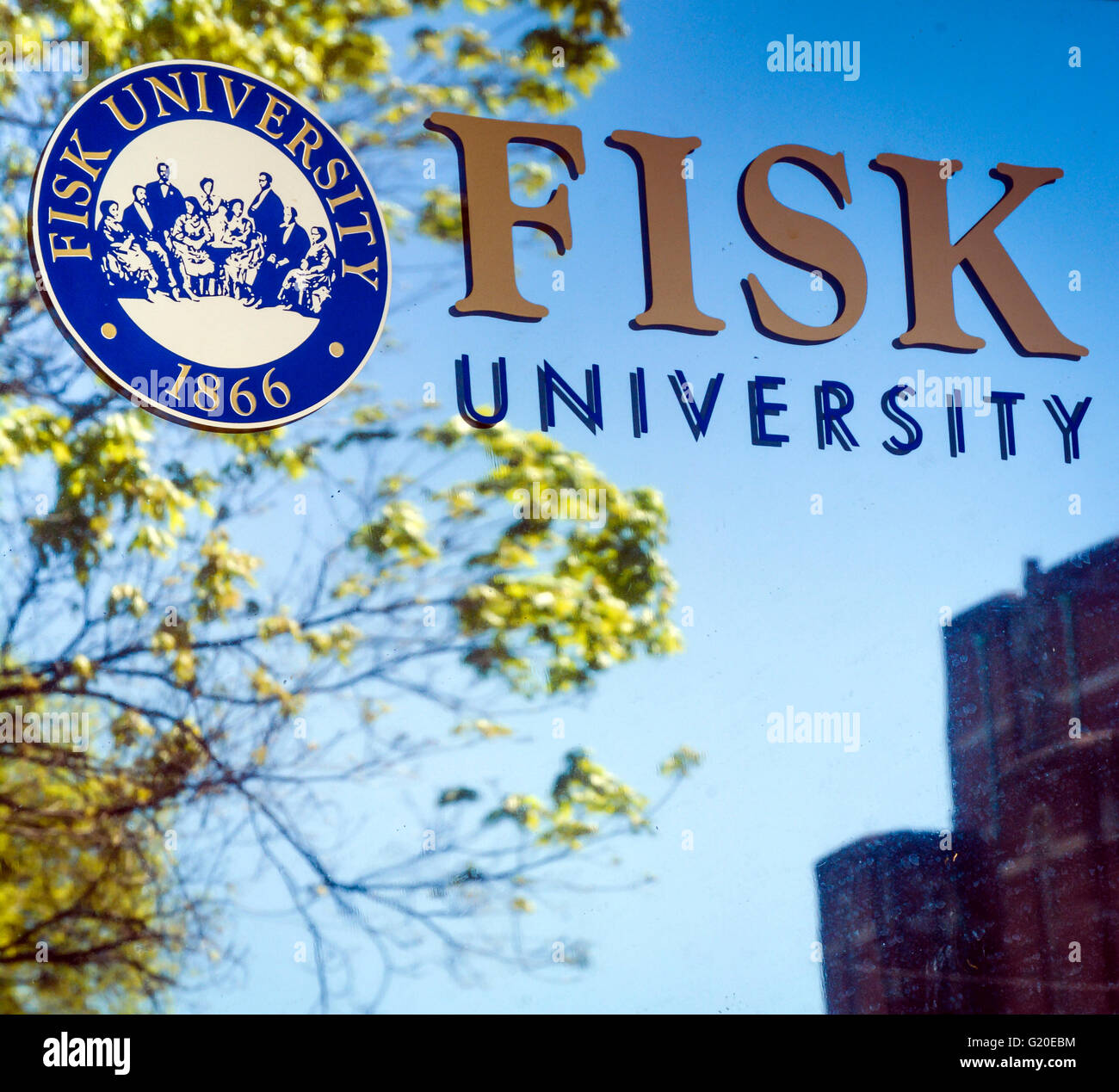 The vibrant Fisk University graphic art logo type and seal reflect off surface of window showing sky and trees and building Stock Photo
