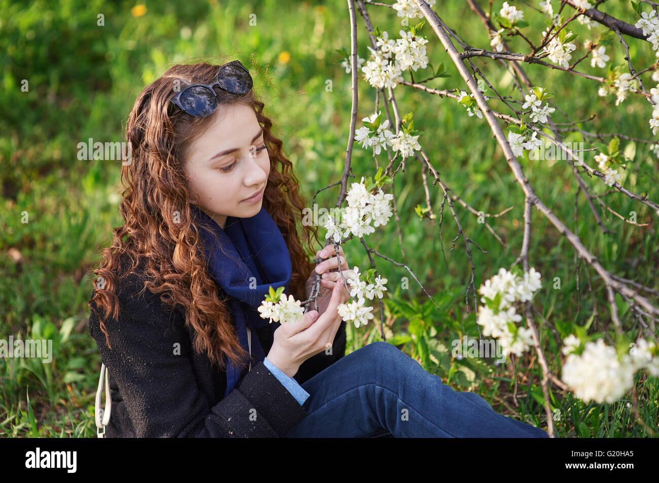 young woman in black coat walking in a blossoming spring garden Stock Photo