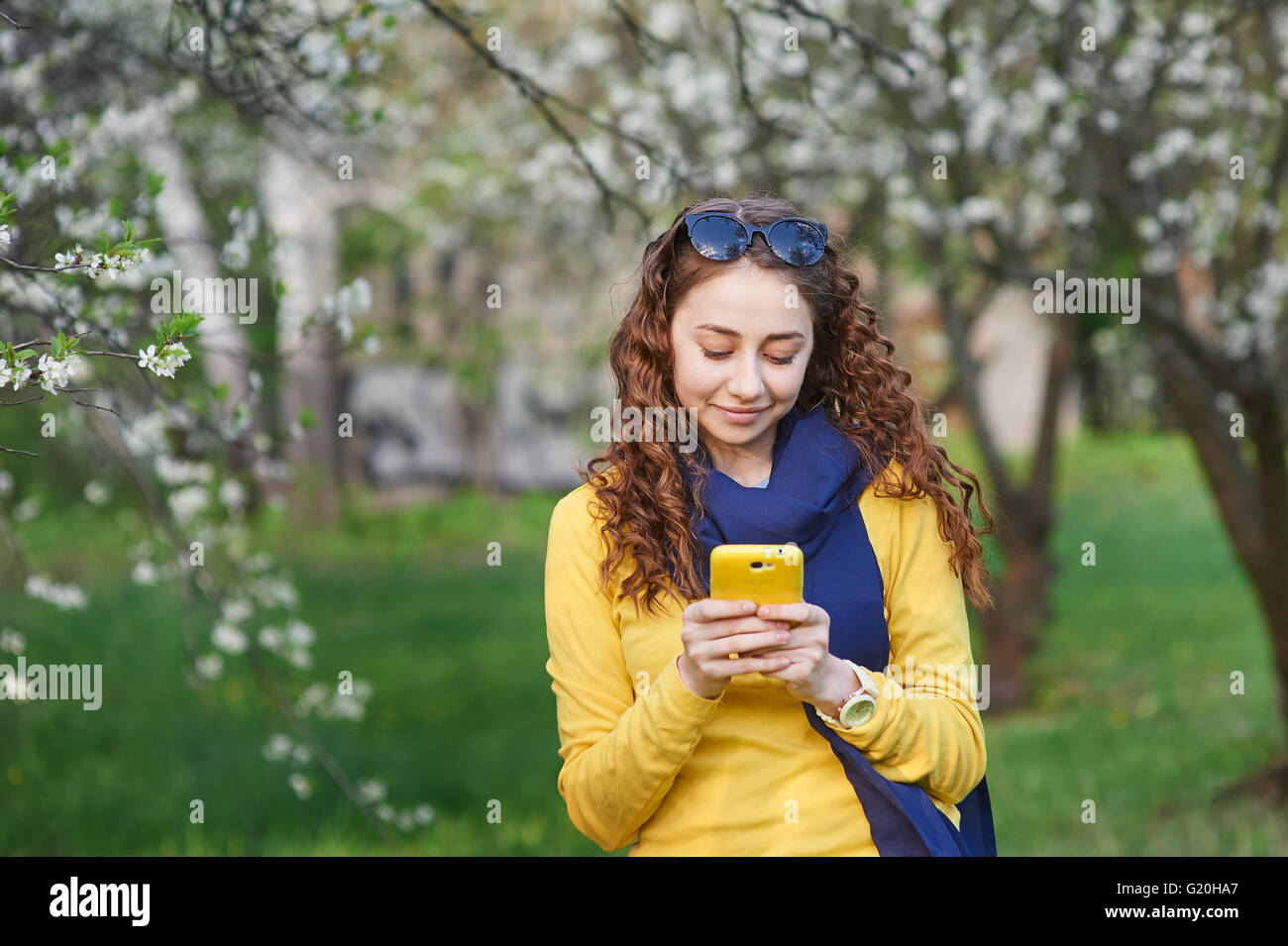 young woman in the blossoming spring garden with smartphone Stock Photo
