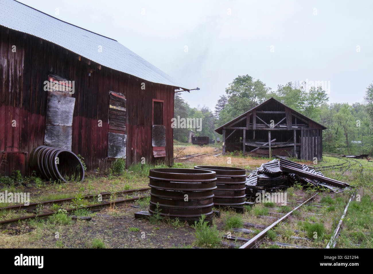 Dilapidated sheds along railroad tracks with rusting train wheels in countryside. Stock Photo