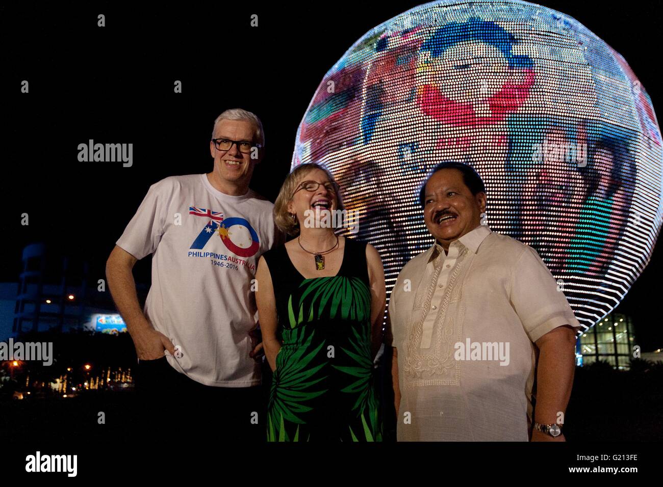 Pasay, Philippines. 21st May, 2016. Ambassador Amanda Gorely (C) laughs while chatting with Australian Embassy Counsellor Richard Rodgers (L), and NHC Executive Director Vic Badoy (R) as they pose in front of the electronic globe billlboard showing the 70th anniversary logo in Pasay CIty. Australian Ambassador to the Philippines Amanda Gorely led the commemorative light up of the SM Mall of Asia Globe with the 70th Anniversary Philippine-Australia logo. Credit:  J Gerard Seguia/Pacific Press/Alamy Live News Stock Photo