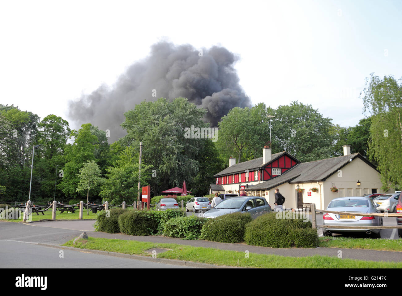 Worcester Park, Surrey, UK. 21st May 2016. Clouds of black, billowing smoke rise from a fire on B284 Old Malden Lane in Worcester Park, Surrey. At around 7.30pm multiple fire crews, police and ambulances attended the fire beside the Hogsmill Toby Carvery Pub. Police have confirmed that burning tyres at an industrial yard caused the excessive amounts of black smoke. By around 8.00pm the fire was under control. Credit:  Julia Gavin UK/Alamy Live News Stock Photo
