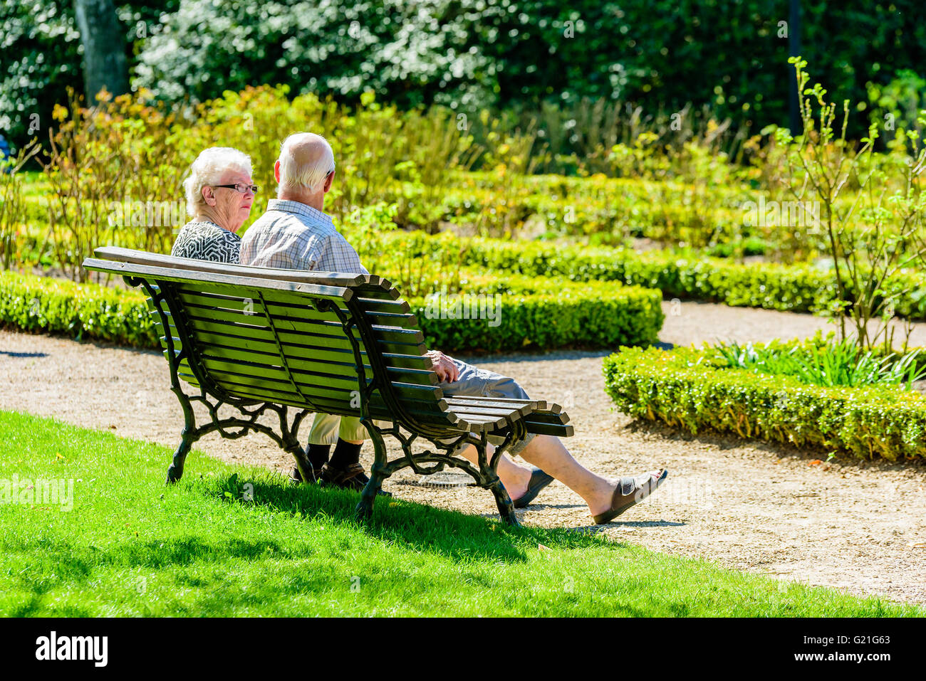 Ronneby, Sweden - May 8, 2016: Real people in everyday life. Here two senior persons rest on a park bench in the sunshine. Stock Photo