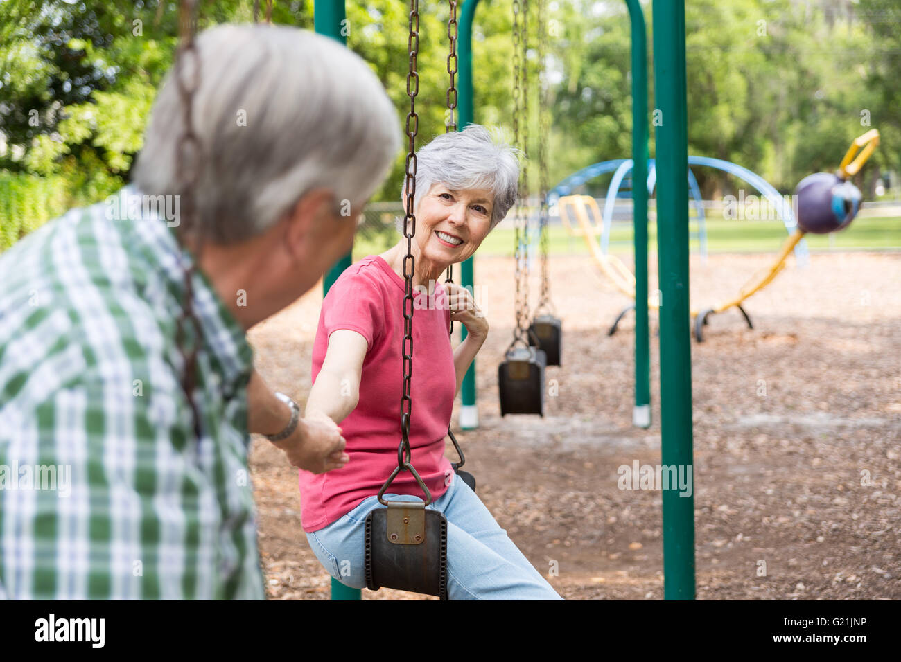 Senior Couple Holding hands on swinging in the park Stock Photo