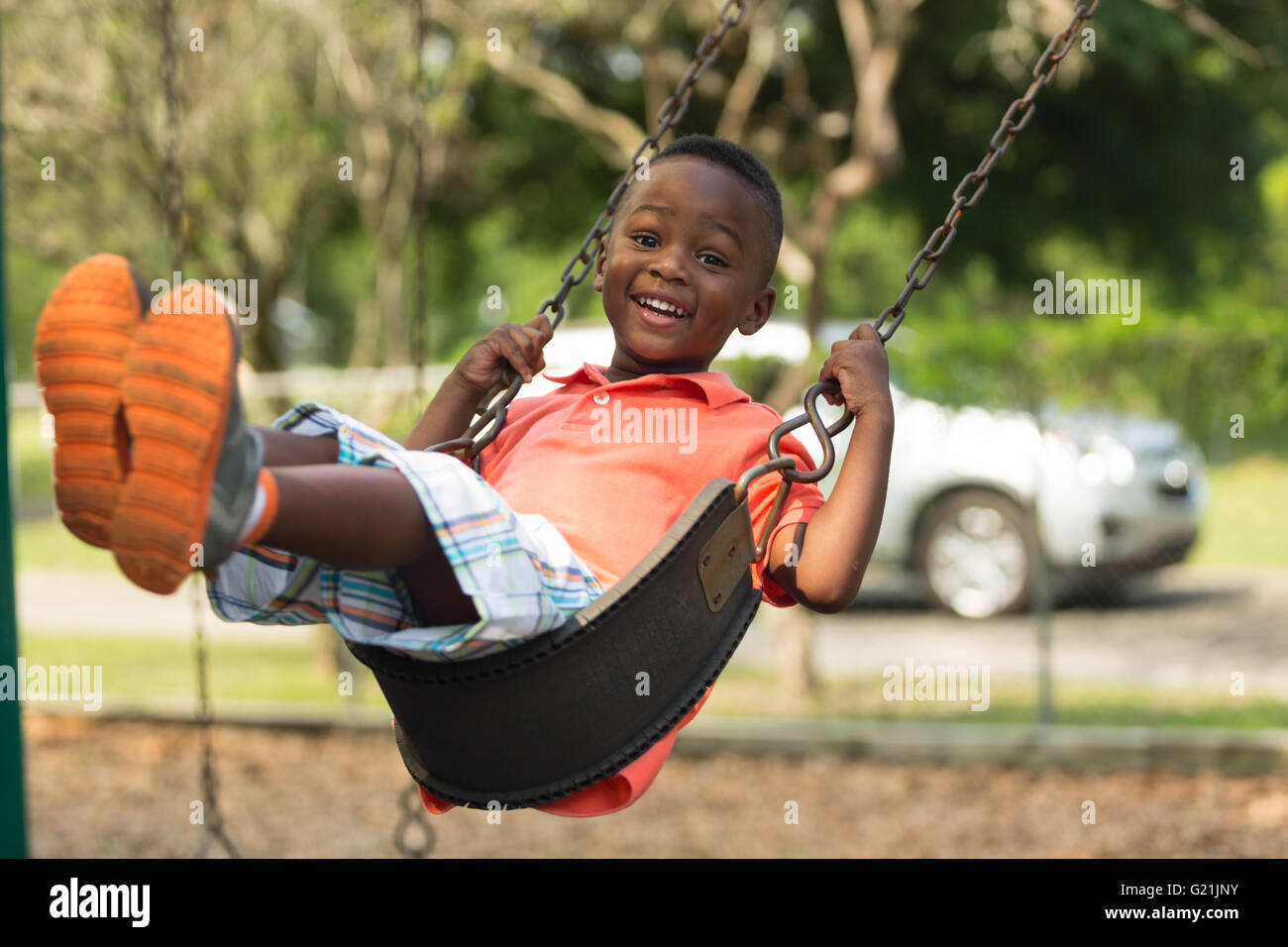 Small child swinging in the park smiling and having fun Stock Photo