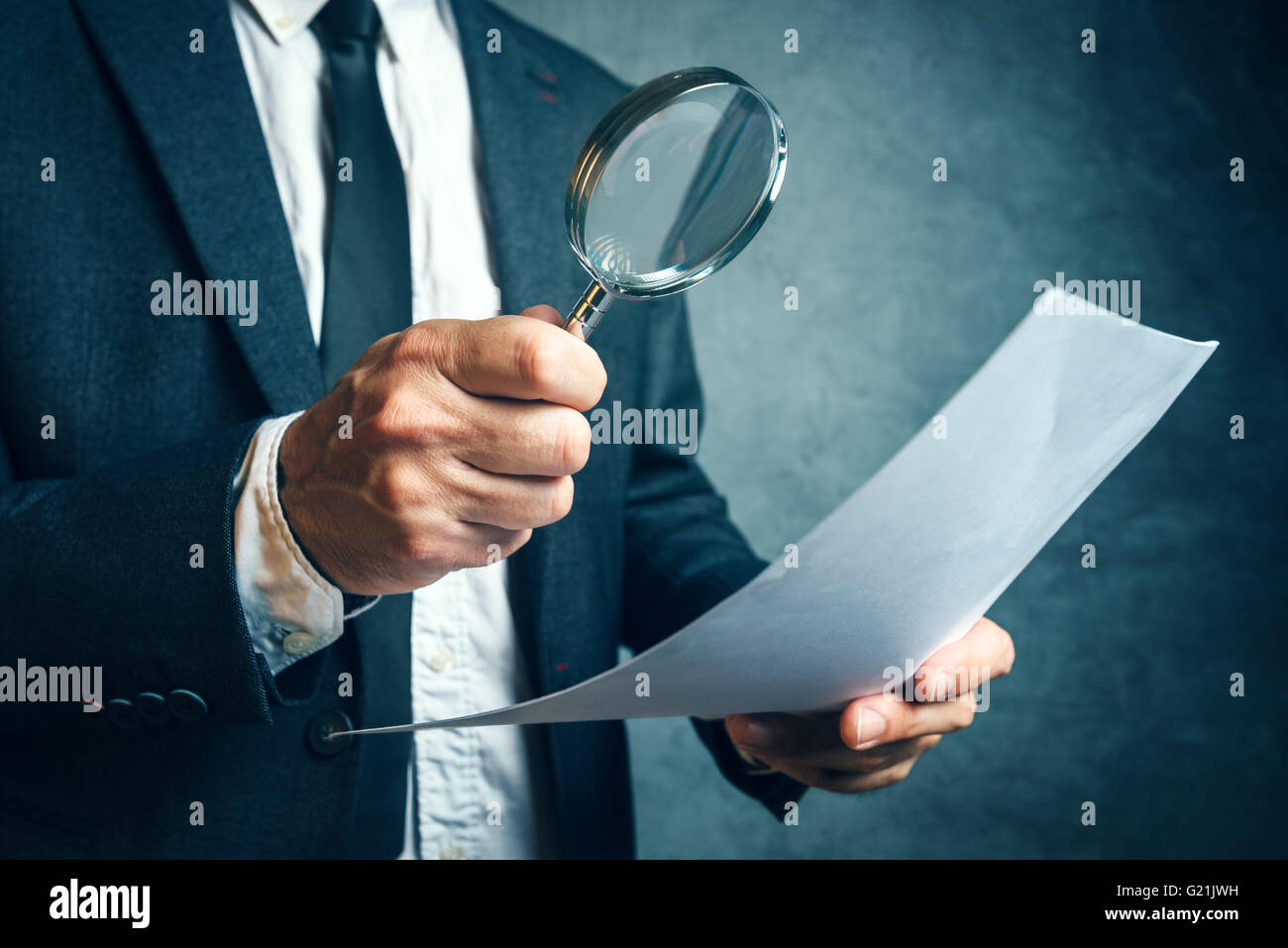 Tax inspector investigating financial documents through magnifying glass, forensic accounting or financial forensics, inspecting Stock Photo