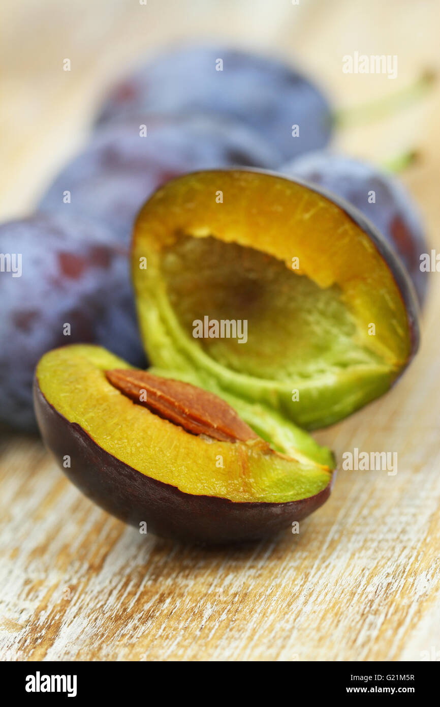 Cross section of a plum on wooden surface, closeup Stock Photo