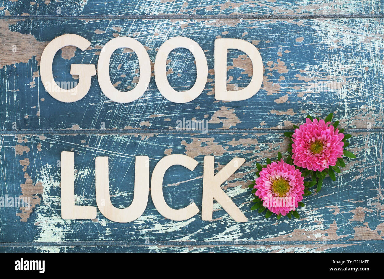 Good luck written with wooden letters on rustic surface and pink