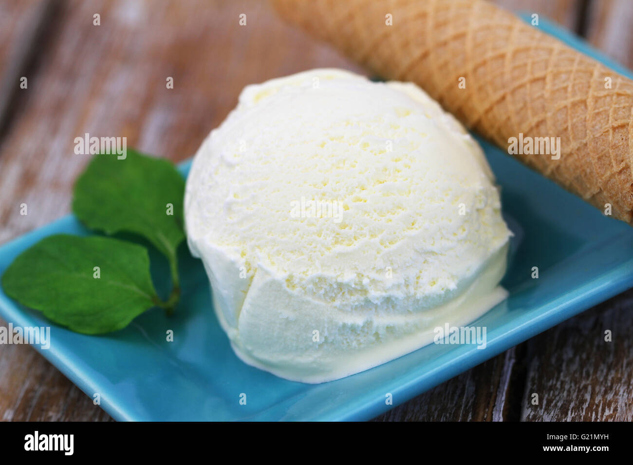 Scoop of vanilla ice cream and wafer on rustic wooden surface Stock Photo