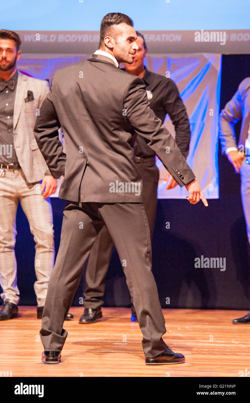 MAASTRICHT, THE NETHERLANDS - OCTOBER 25, 2015: Male fitness model dressed in suit shows his best on stage Stock Photo
