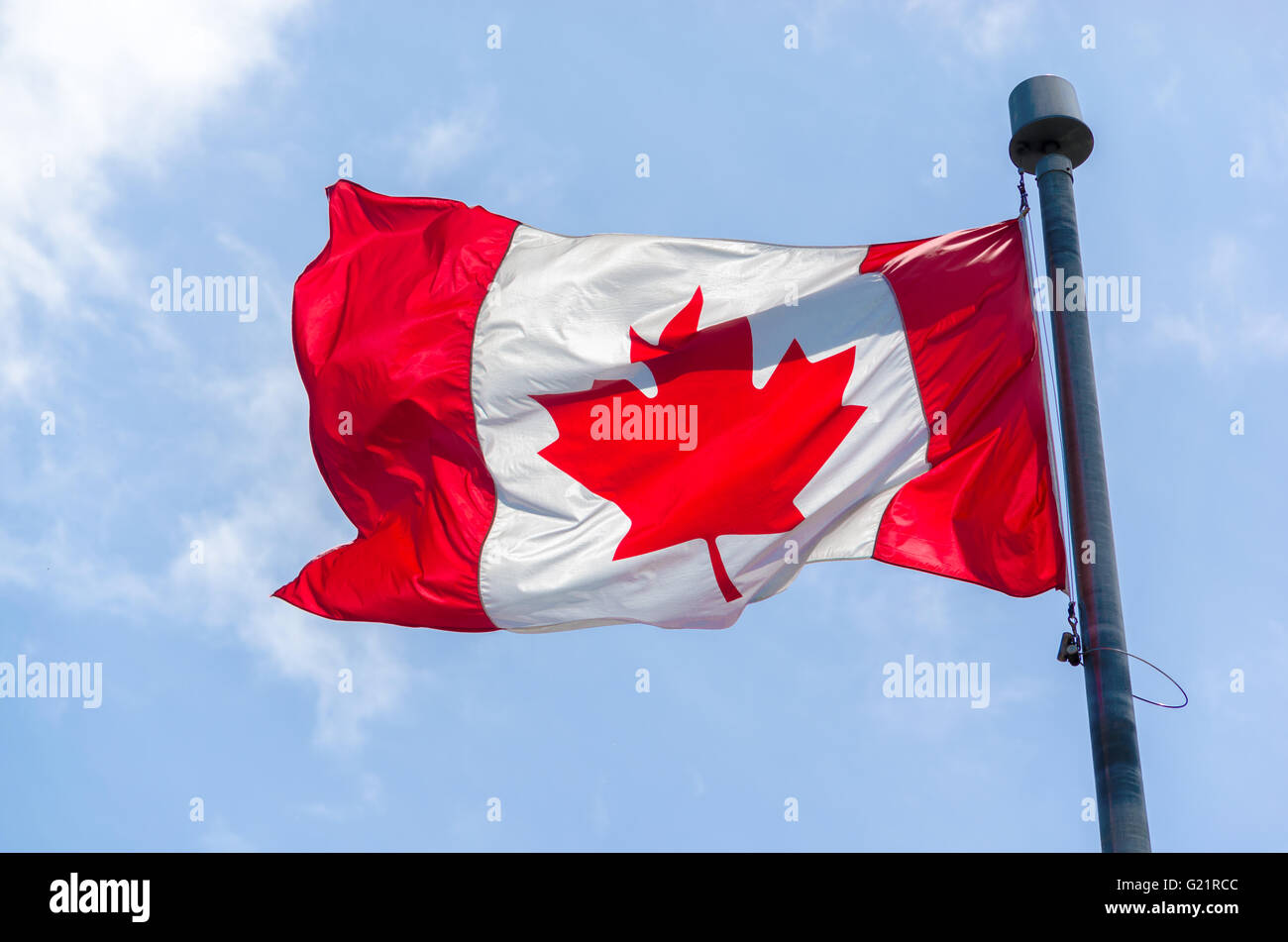 Canadian Flag in the wind over blue sky with clouds Stock Photo