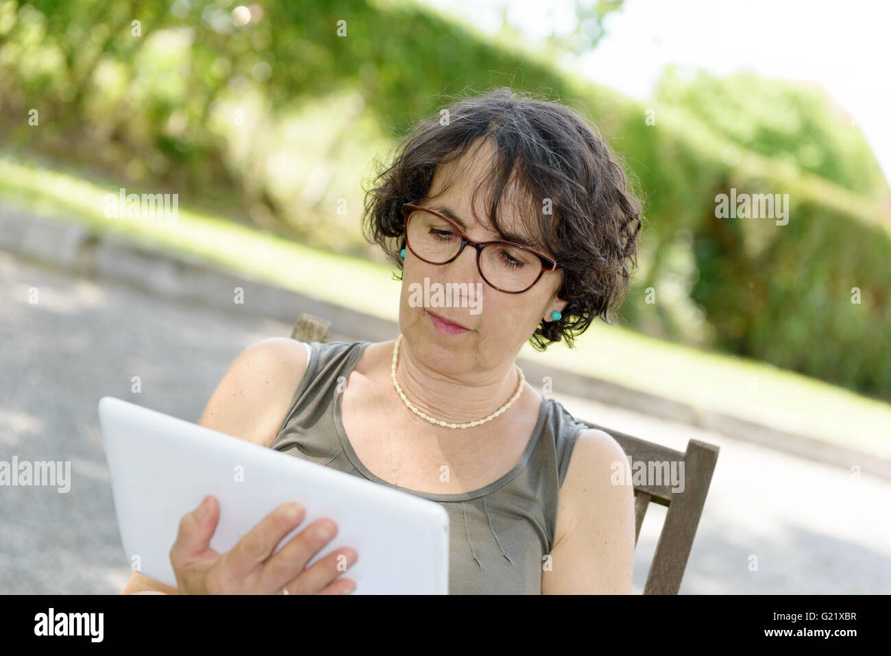a charming  woman with a tablet in her garden Stock Photo
