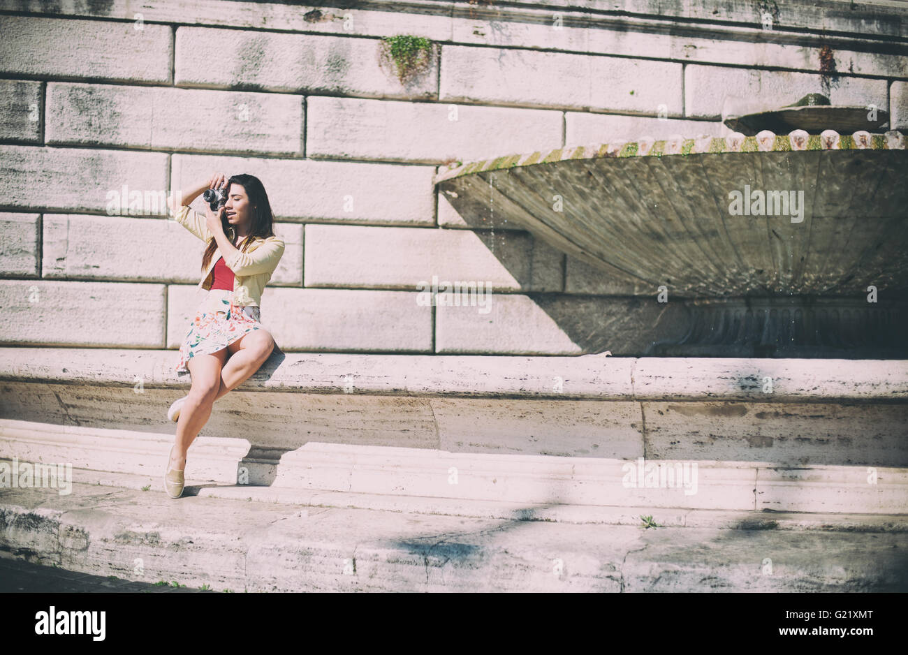 Young tourist woman taking picture with vintage camera outdoor in place of Rome Stock Photo