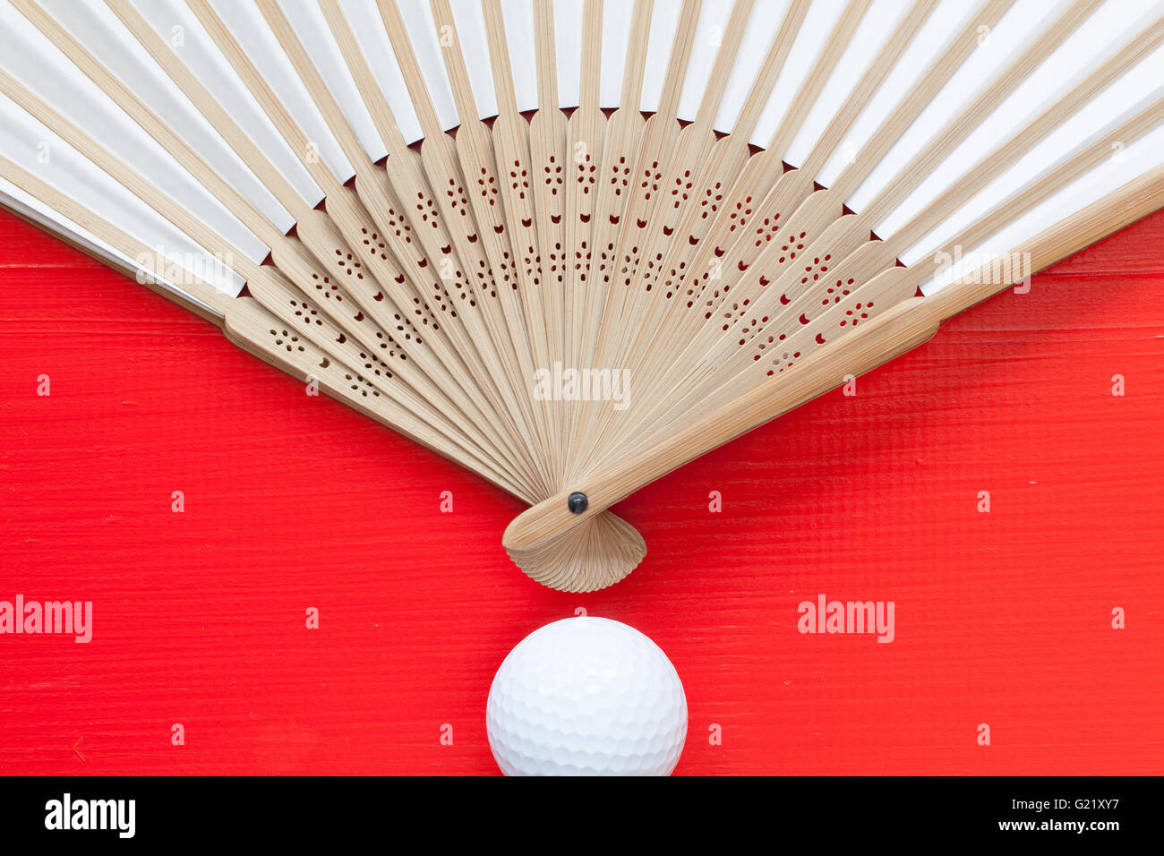 Typical Japanese hand fan made and golf ball on the wooden red table