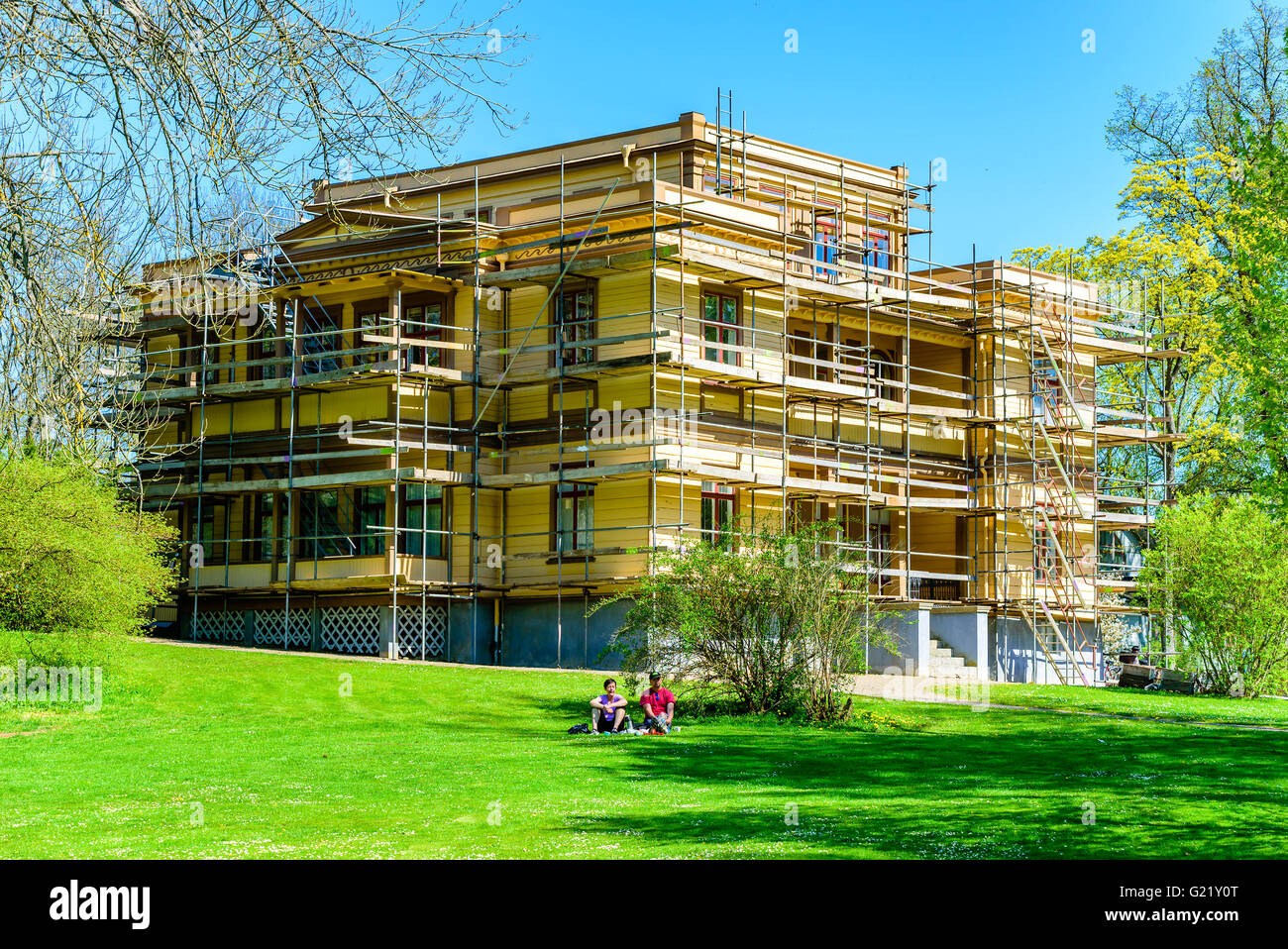 Ronneby, Sweden - May 8, 2016: Scaffoldings around the Italian villa. Two persons resting on a blanket in front of the house. Stock Photo